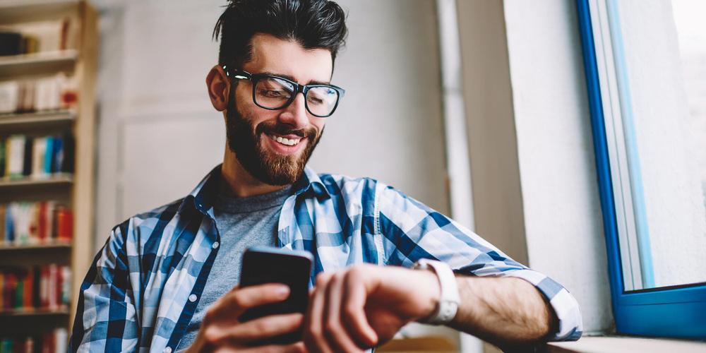 Mann nutzt ein Smartphone und eine Smartwatch gleichzeitig