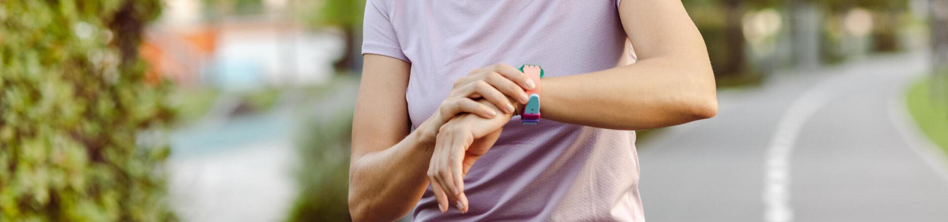 Frau beim Joggen schaut auf ihre Smartwatch