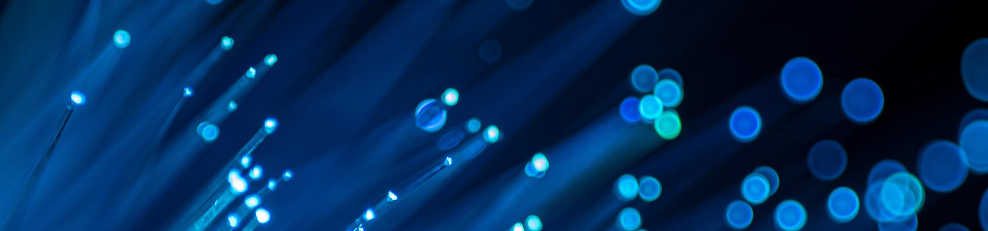 Nahaufnahme von Glasfasern mit leuchtenden blauen Lichtpunkten