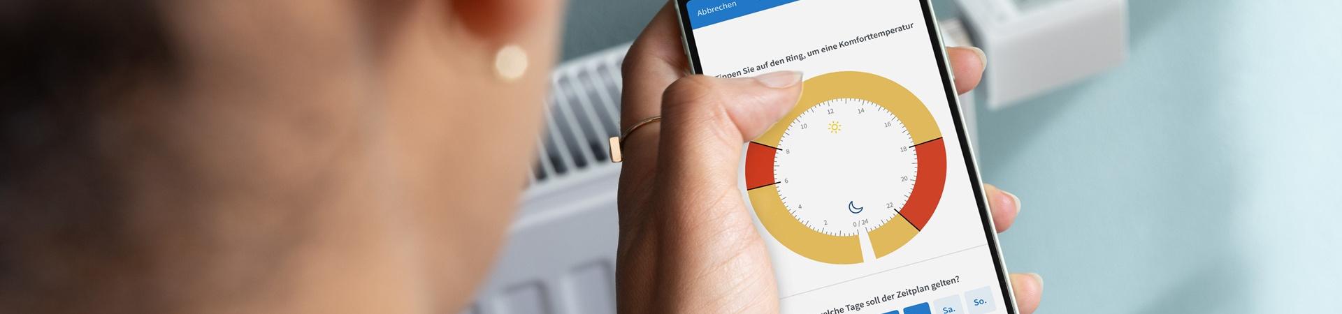 Person schaut auf ihr Handy, mit dem sie die Heizung reguliert