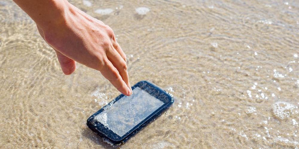 Smartphone ist ins Wasser gefallen und eine Person greift danach