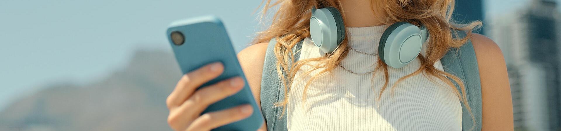 Eine Person guckt lächelnd auf ihr Smartphone