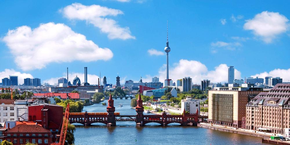 Stadtansicht von Berlin mit Oberbaumbrücke, Spree und Fernsehturm bei blauem Himmel.