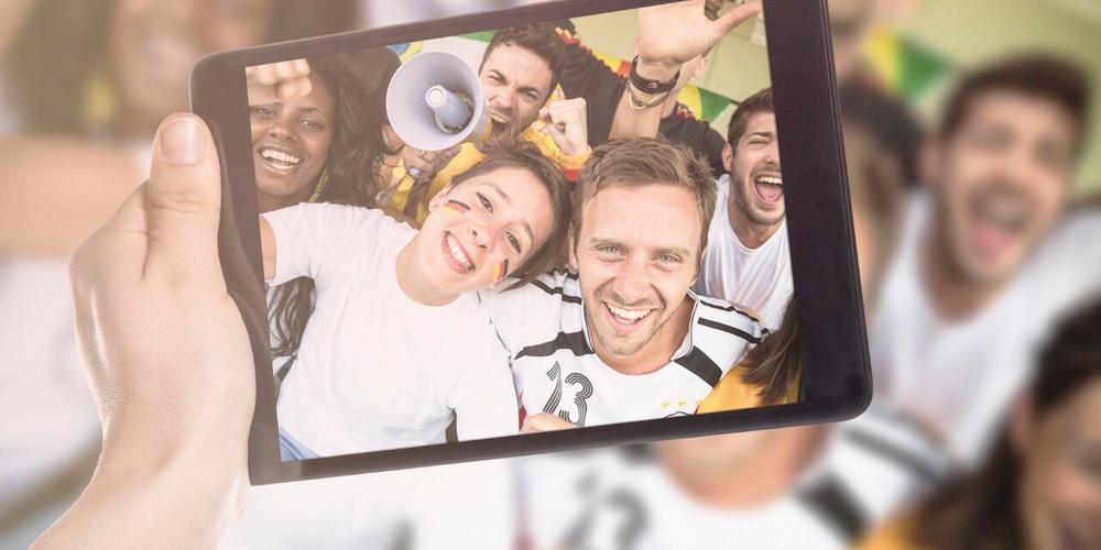 Jubelnde Fußballfans machen ein Selfie mit einem Tablet
