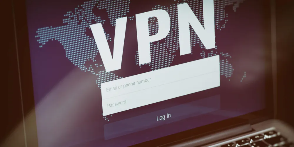 Laptop-Bildschirm mit VPN-Anmeldung vor einer digitalen Weltkarte