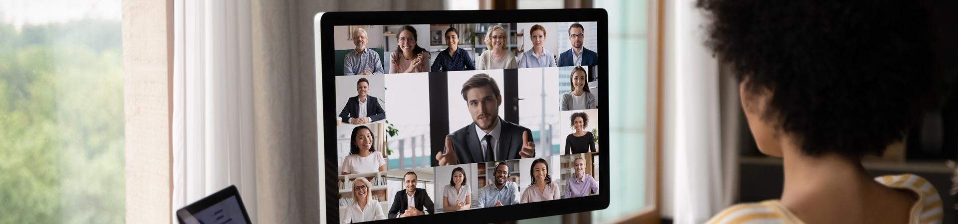 Person sitzt am Schreibtisch und nimmt an einer Videokonferenz teil