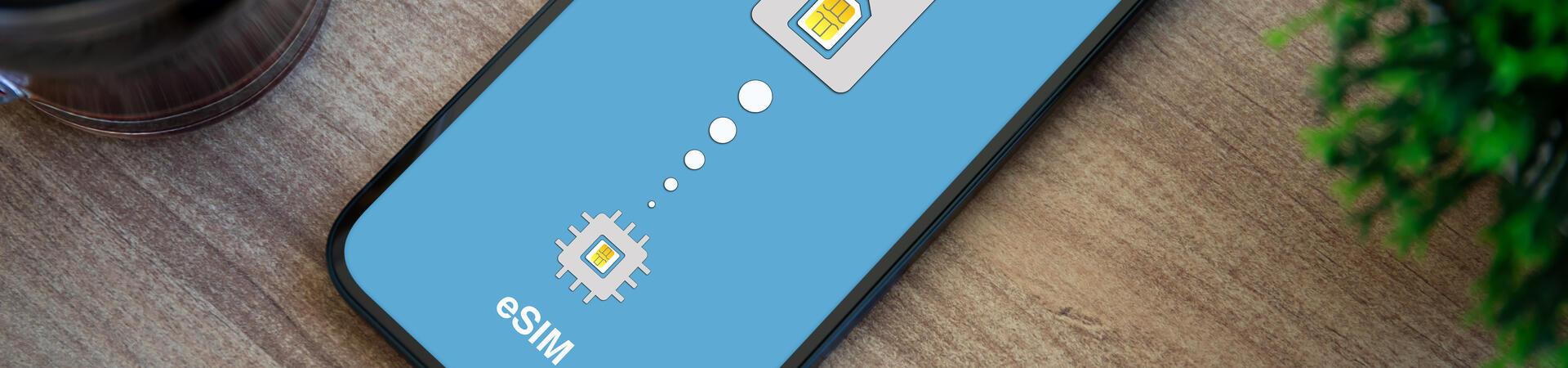 Smartphone mit Darstellung des Wechsels von physischer SIM-Karte zu eSIM auf einem Holztisch