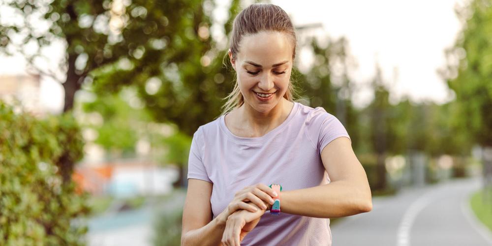 Frau beim Joggen schaut auf ihre Smartwatch