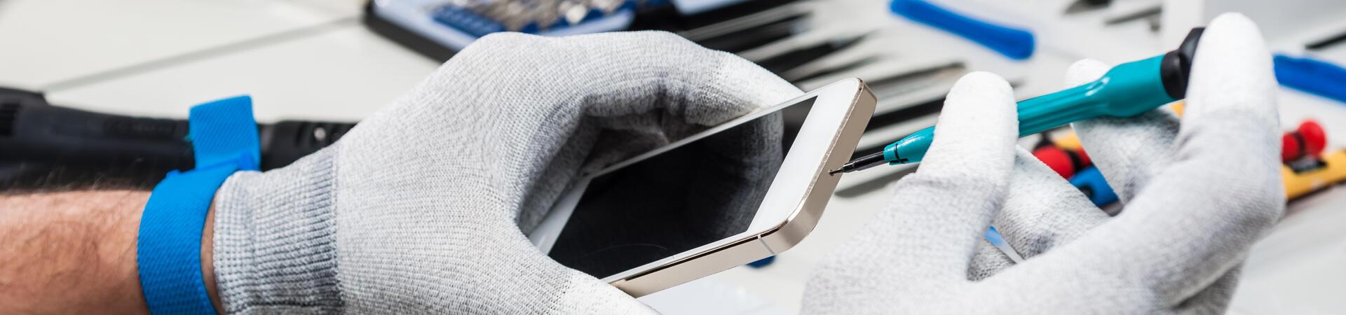 Ein Mensch repariert ein Smartphone auf einer Arbeitsfläche