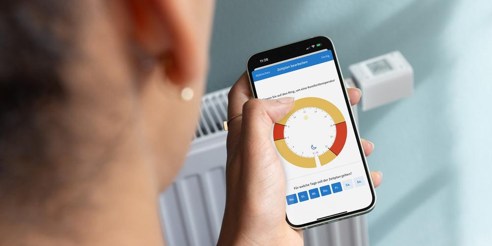 Person schaut auf ihr Handy, mit dem sie die Heizung reguliert