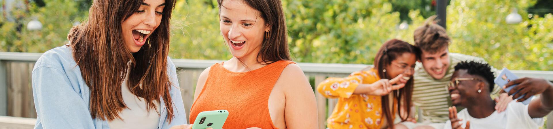 Zwei Frauen gucken freudig auf ein Smartphone