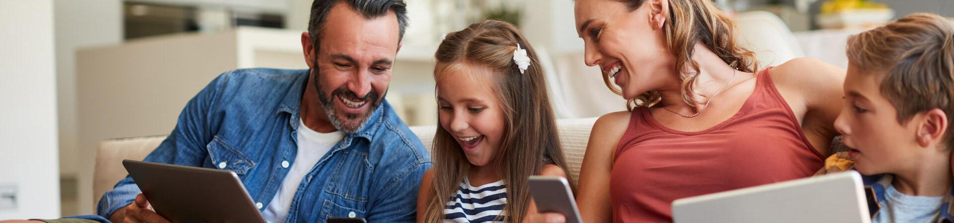 amilie sitzt gemeinsam auf dem Sofa und nutzt verschiedene digitale Geräte