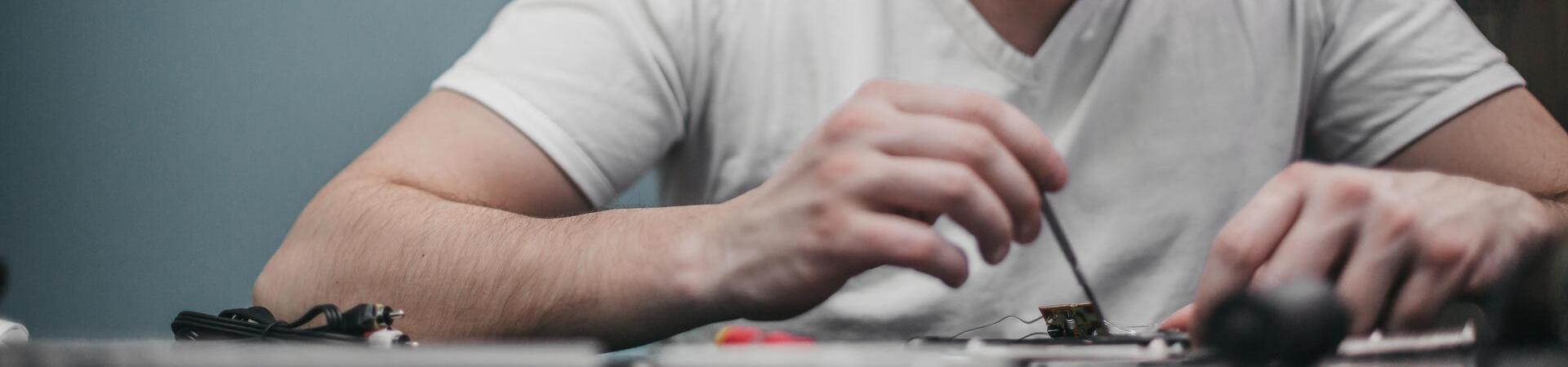 Person repariert ein Smartphone an einem Arbeitstisch