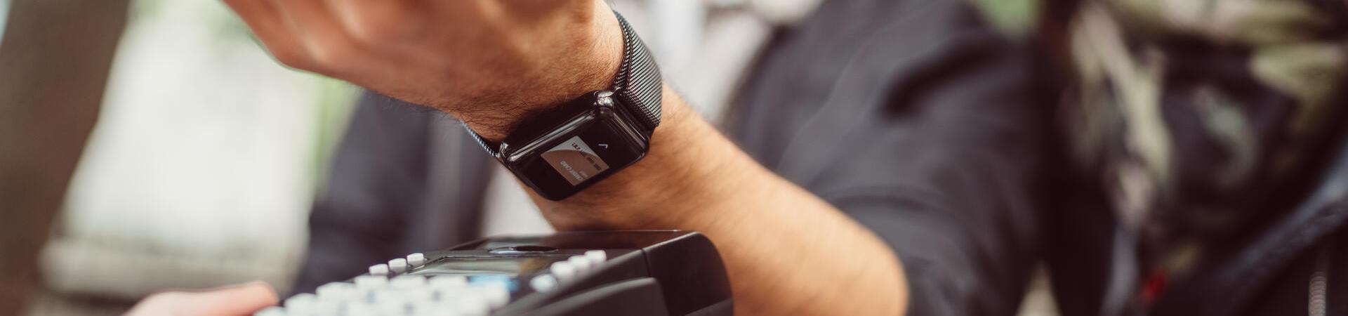 Mann bezahlt mit seiner Smartwatch an einem Kartenlesegerät
