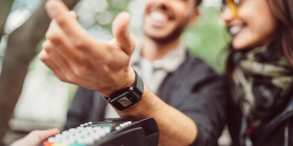 Mann bezahlt mit seiner Smartwatch an einem Kartenlesegerät