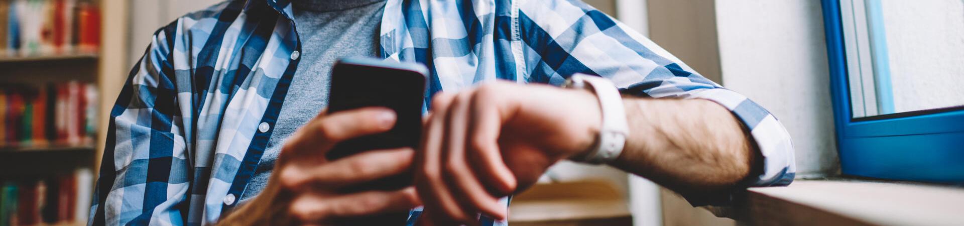 Mann nutzt ein Smartphone und eine Smartwatch gleichzeitig