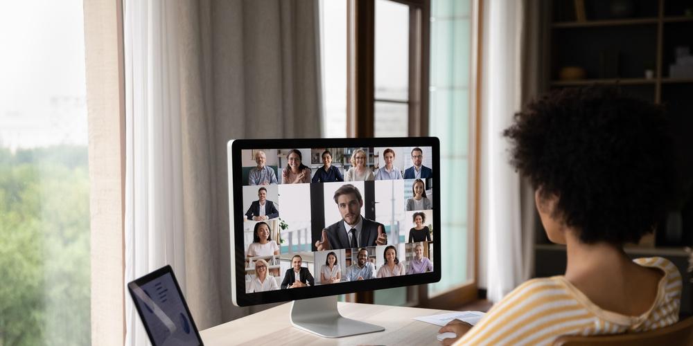 Person sitzt am Schreibtisch und nimmt an einer Videokonferenz teil