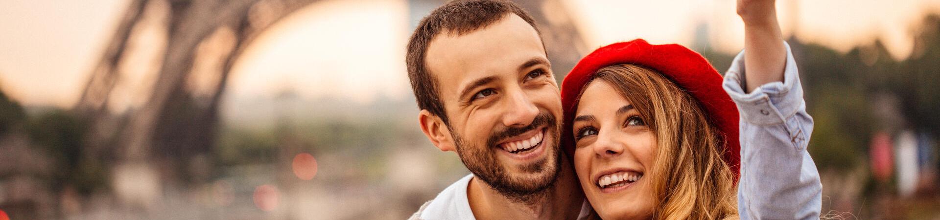 Eine Frau und ein Mann fotografieren sich mit einem Smartphone vor dem Eiffelturm in Paris