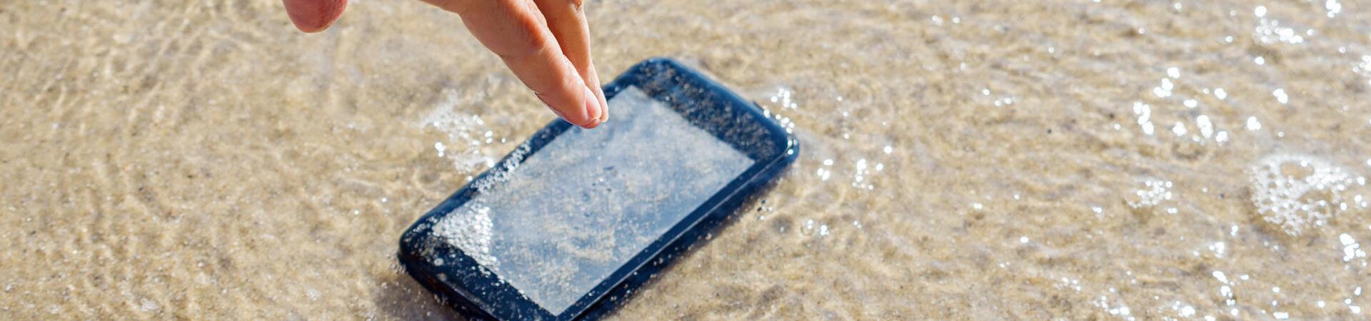 Smartphone ist ins Wasser gefallen und eine Person greift danach