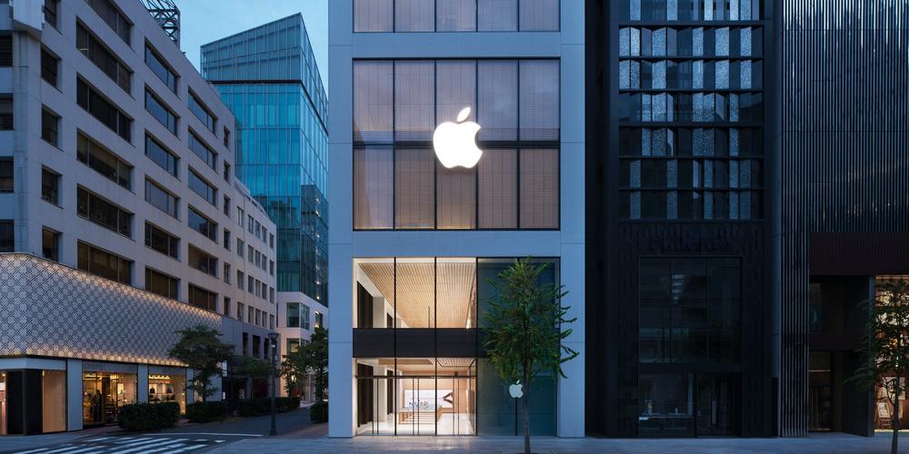 Apple Store mit großem leuchtendem Apple-Logo zwischen modernen Gebäuden in einer ruhigen Straße bei Dämmerung in Tokio
