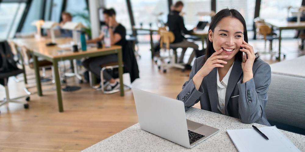 Eine Frau sitzt in einem Büro an ihrem Schreibtisch und telefoniert