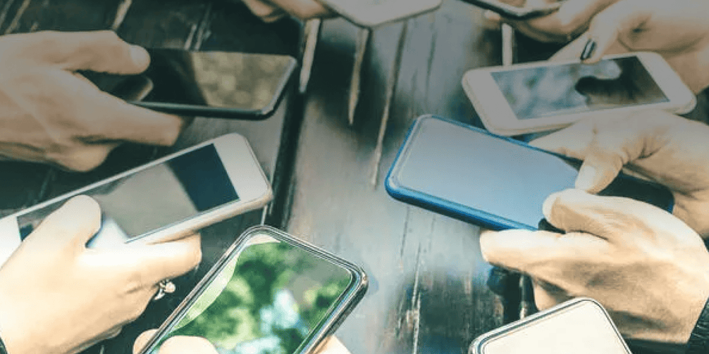 Personengruppe am Tisch mit Smartphones in der Hand