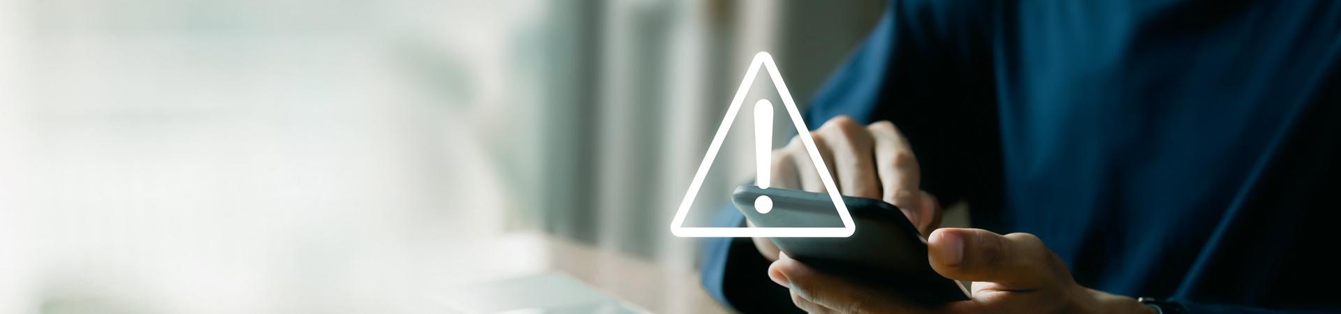 Person nutzt ein Smartphone und ein Warnsymbol über dem Display zeigt eine Internetstörung an