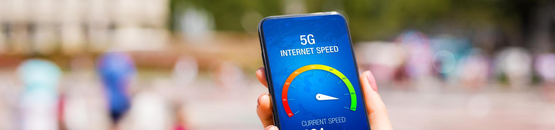 Eine Hand hält ein Smartphone auf dessen Display man einen 5G-Speedtest sieht