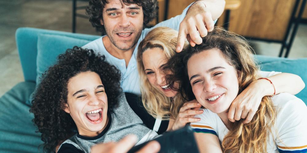 4 Personen sitzen auf einer couch machen ein Selfie und lachen in die Kamera
