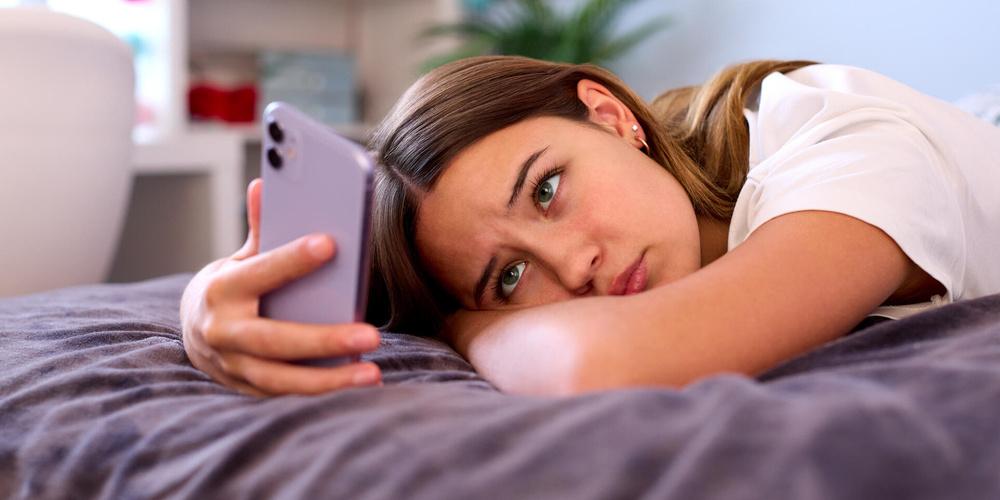 Frau schaut bedrückt auf ihr Handy
