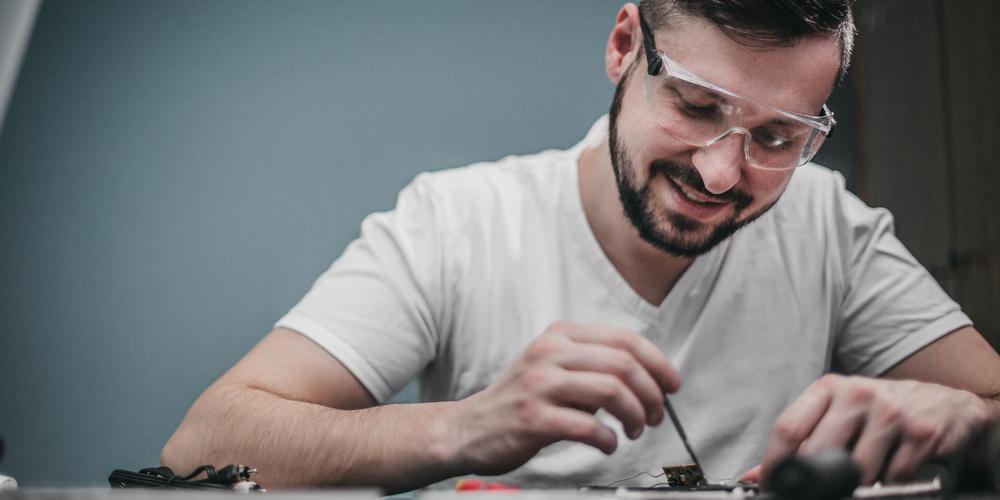 Person repariert ein Smartphone an einem Arbeitstisch