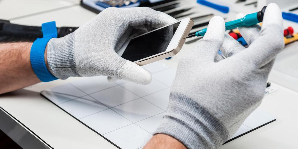 Ein Mensch repariert ein Smartphone auf einer Arbeitsfläche