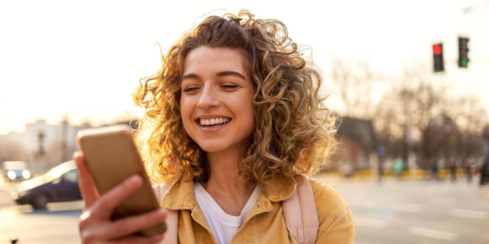 Frau schaut lachend auf ihr Handy 