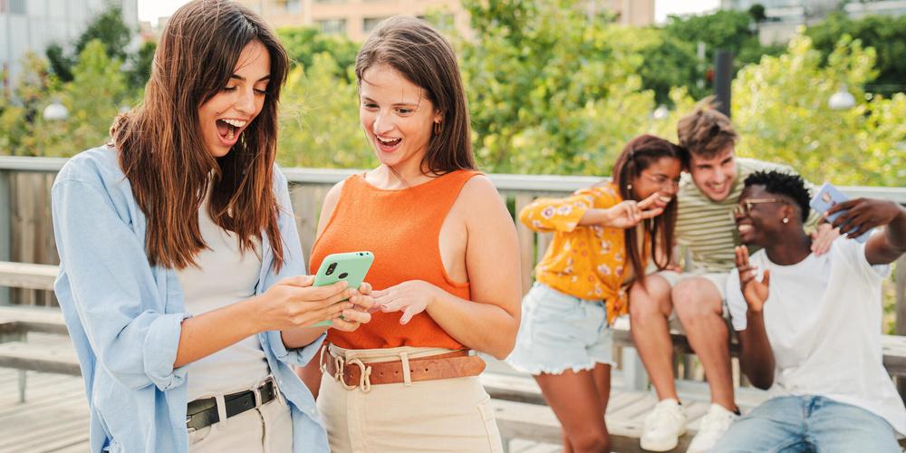 Zwei Frauen gucken freudig auf ein Smartphone