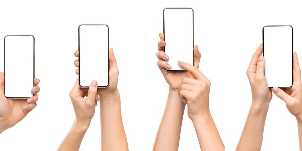 Hände halten verschiedene Smartphones mit leeren Displays vor weißem Hintergrund