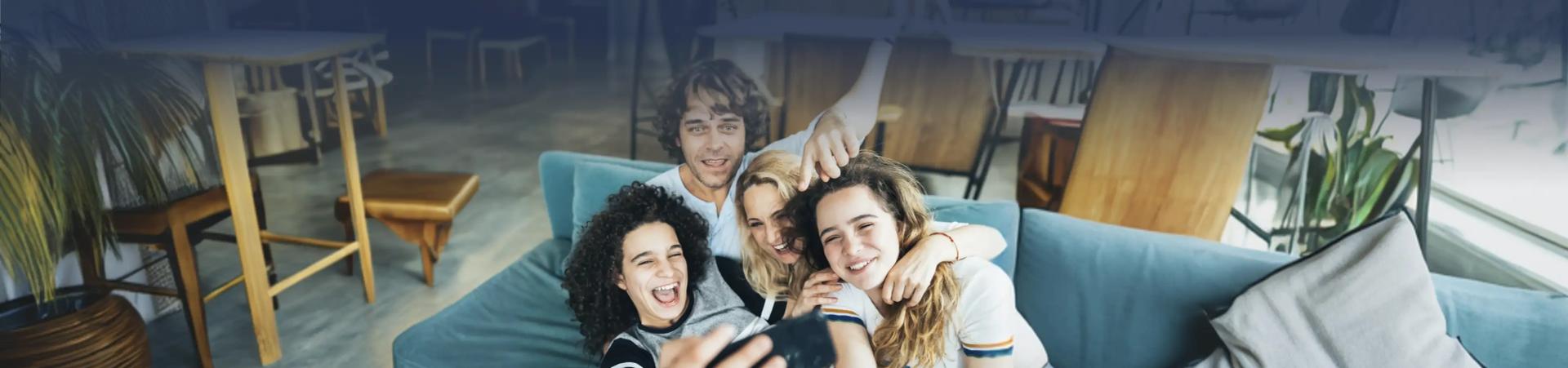 4 Personen sitzen auf einer couch machen ein Selfie und lachen in die Kamera