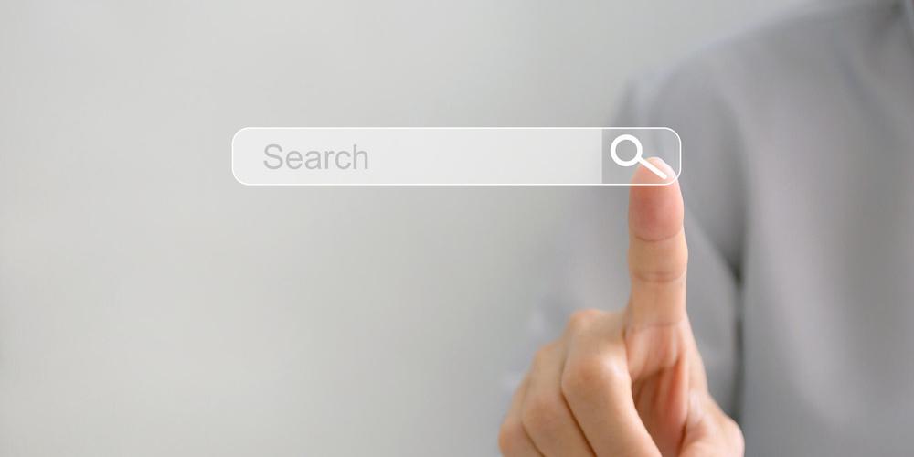 Finger tippt auf ein digitales Suchfeld mit Lupensymbol