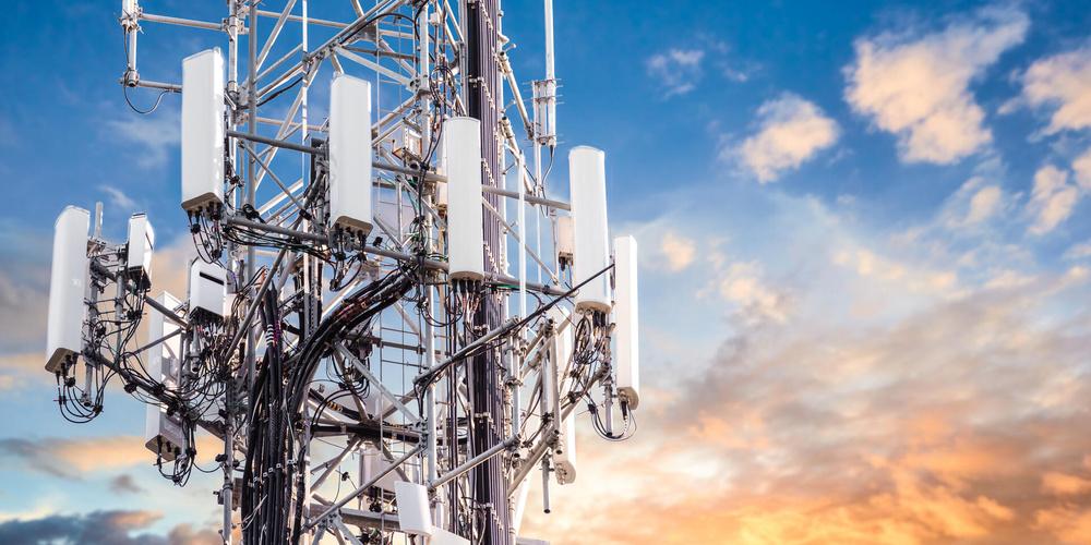 Mobilfunkmast mit mehreren Antennen vor Himmel bei Sonnenuntergang