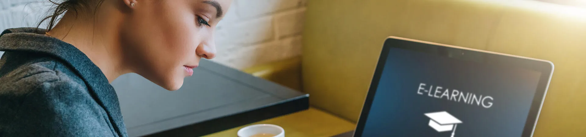 Studentin lernt mit Laptop und Notizbuch an einem Tisch