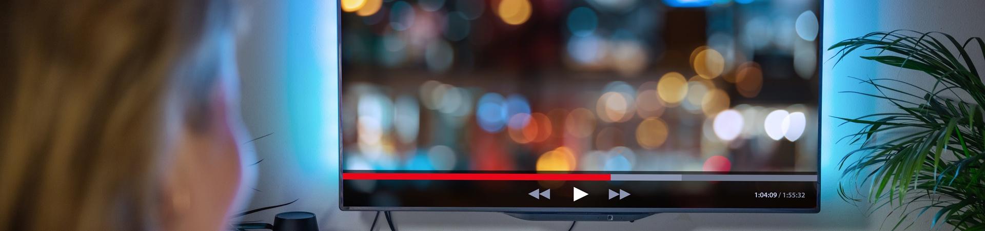 Person sitzt vor einem Fernseher und streamt einen Film