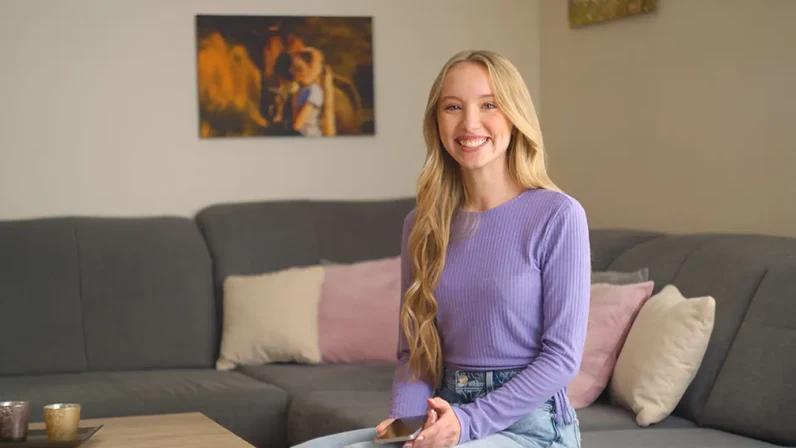 junge frau auf couch mit handy lacht