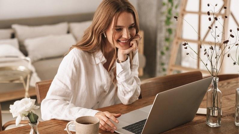 frau sitzt laechelnd vor dem laptop