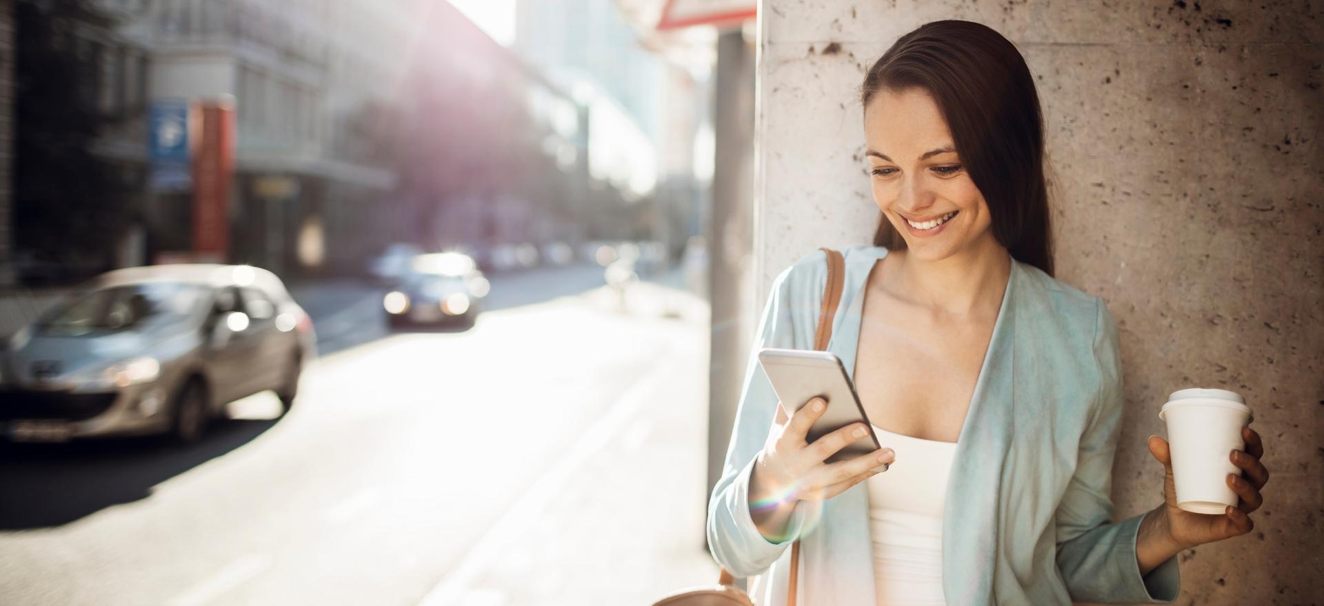 frau mit handy steht auf fussweg vor hauswand | 1&1 frau mit handy steht auf fussweg vor hauswand